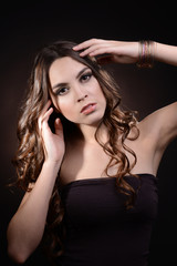 Fototapeta premium Beautiful young woman with long hair on dark brown background