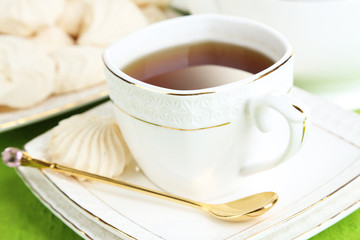 Cup of tea with meringues on table close-up