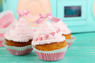 Tasty cup cakes with cream on blue wooden table
