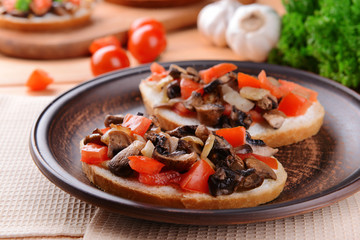 Delicious bruschetta with mushrooms on plate on table close-up