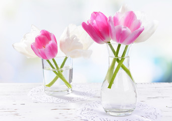 Beautiful tulips in bucket in vase on table on light background