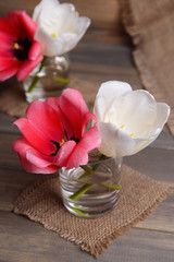 Beautiful tulips in bucket in vase on table on grey background