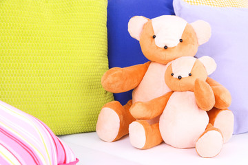 Two bears toy with pillows on sofa