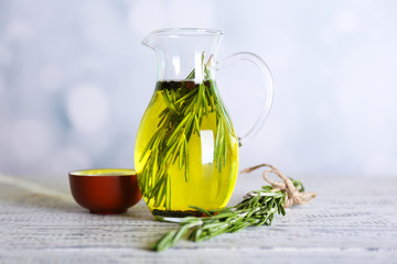 Essential Oil with rosemary in glass jug, on light background