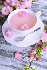 Beautiful fruit blossom with cup of tea on table close-up