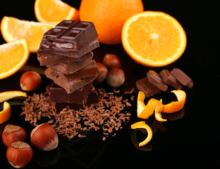 Chocolate, orange and  hazelnuts on black background