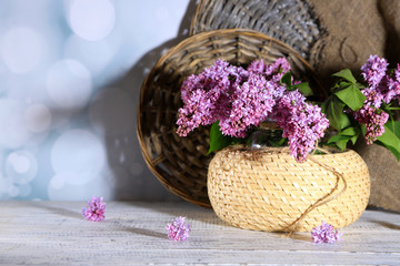 Fototapeta na wymiar Beautiful lilac flowers in wicker vase,