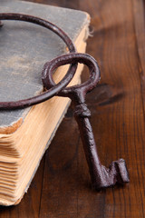 Old key with old book on wooden background