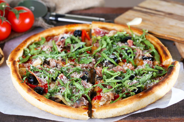 Pizza with arugula on color wooden background