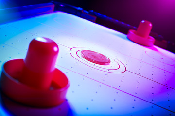 Dramatic lit air hockey table with puck and paddles