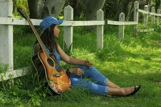 View of a beautiful young country girl with a guitar