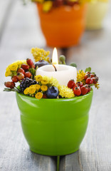 Candle holder decorated with autumn flowers and other plants