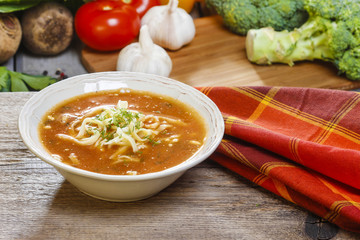 Bowl of tomato soup. Fresh vegetables in the background