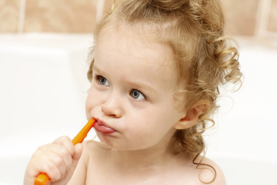 Little girl cleaning her teeth in the bath