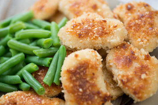 Close-up of sesame chicken nuggets with beans, horizontal shot