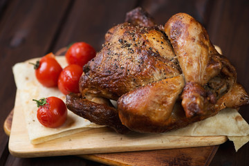 Whole baked chicken with tomatoes on pita bread, close-up