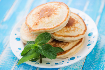 Glass plate with homemade fritters over blue wooden background