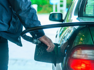 Car refuel fueling at the filling station, holding a fuel pump