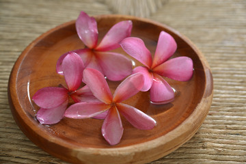 frangipani in water wooden bowl on Brown straw mat