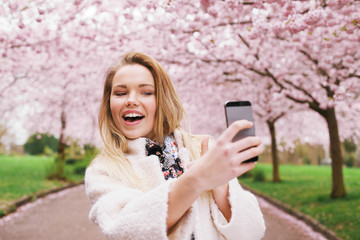 Happy young woman photographing herself at park