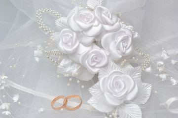 Wedding rings on bridal veil with white boutonniere on gray - obrazy, fototapety, plakaty