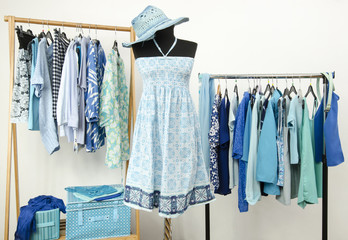 Wardrobe with blue clothes,summer dress with hat on a mannequin.