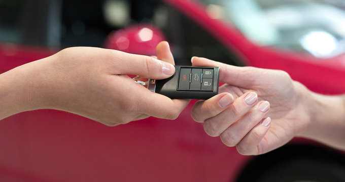 Car saleswoman handing over the keys for a new car