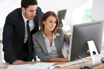 Manager with businesswoman working on desktop