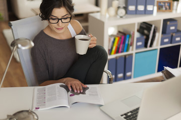 Attractive woman reading magazine at home