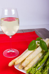 Weißweinglas mit Spargelteller auf rotem Set