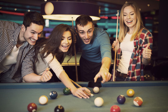 Friends cheering while their friend aiming for billiards ball
