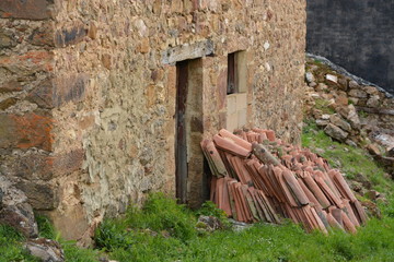 monton de tejas apiladas contra una casa de piedra © uzkiland