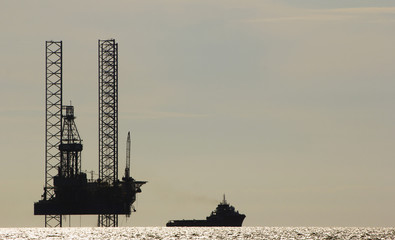 Silhouette of an offshore drilling rig and supply vessel