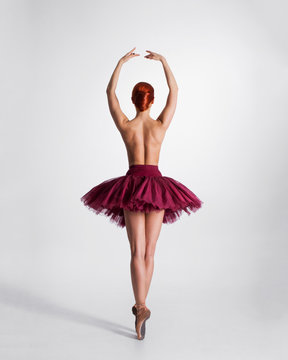 Young naked redhead female ballet dancer in a studio