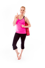Young woman carrying exercise mat smiling and pointing up