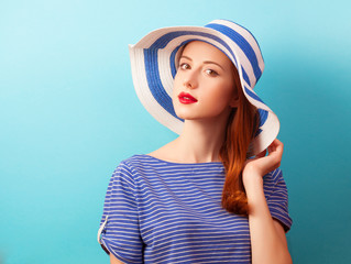 Naklejka premium Redhead girl in hat on blue background.