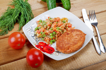 Fish cutlet with vegetables on a rural table