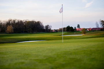 Golf Green with flag with some house in the far distance