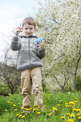 Boy searching Easter eggs among grass