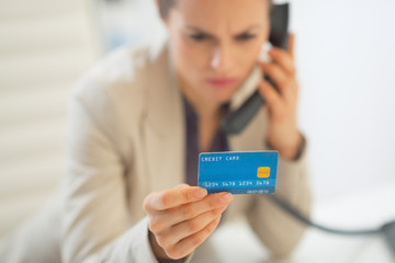 Closeup on business woman with credit card talking phone