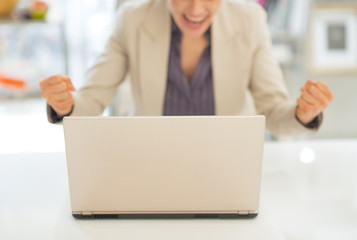 Closeup on laptop and happy business woman in background