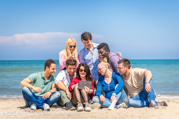 Friends on the beach looking tablet