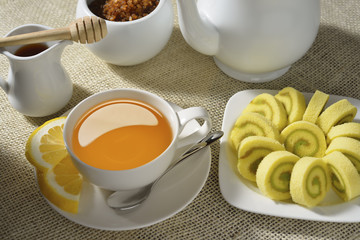 Cup of tea with lemon and cakes on table