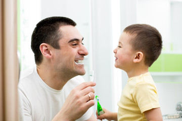 child boy and his dad cleaning teeth in bathroom