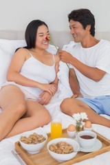 Obraz na płótnie Canvas Happy couple having breakfast in bed