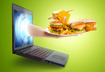 Hand holding a plate with food coming out of a laptop screen