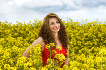 Beautiful young  woman in red dress in yellow field