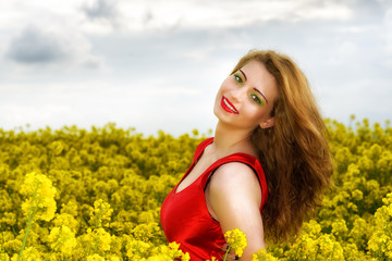 Naklejka na ściany i meble Beautiful young woman in red dress in yellow field
