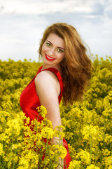 Naklejka na ściany i meble Beautiful young woman in red dress in yellow field