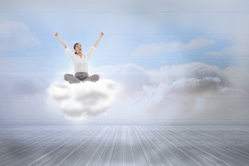 Composite image of cheering businesswoman sitting cross legged